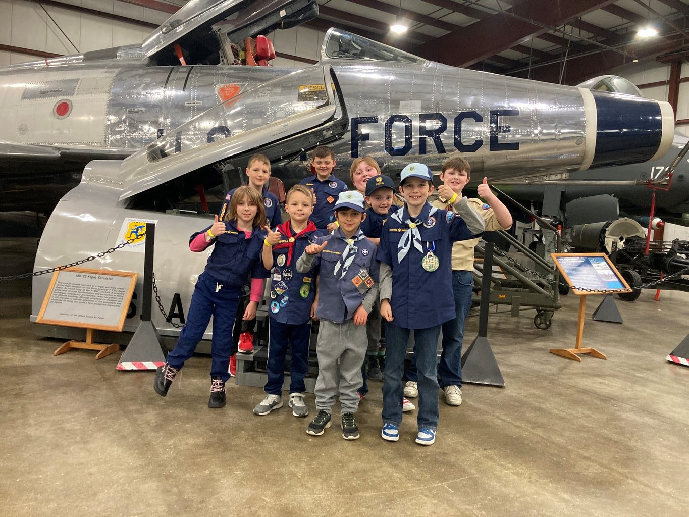 Cub Scouts giving thumbs up in front of an Air Force jet at the New England Air Museum.