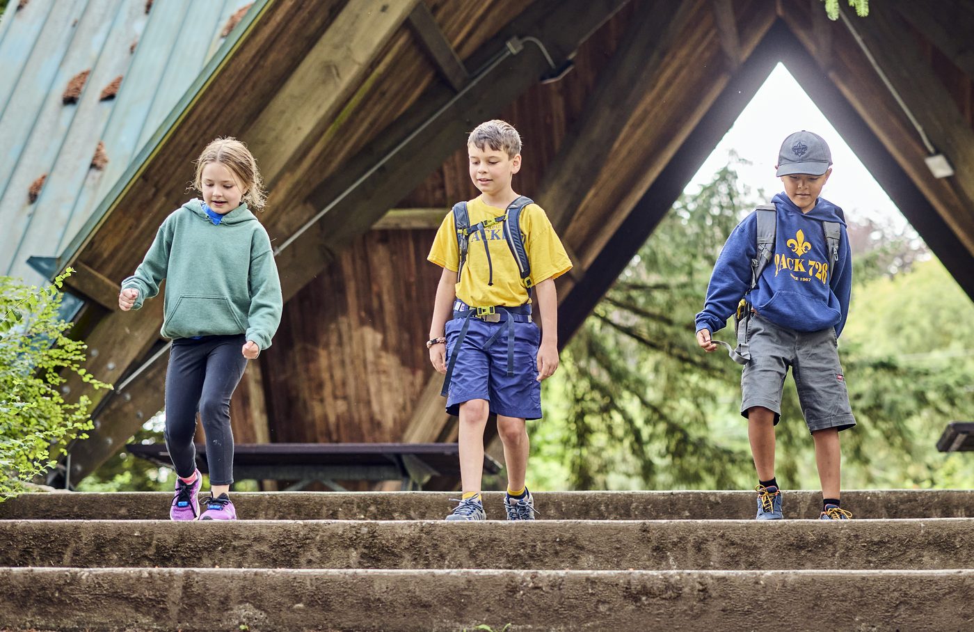 Three Cub Scouts walking down the steps of a trail shelter on a hike.