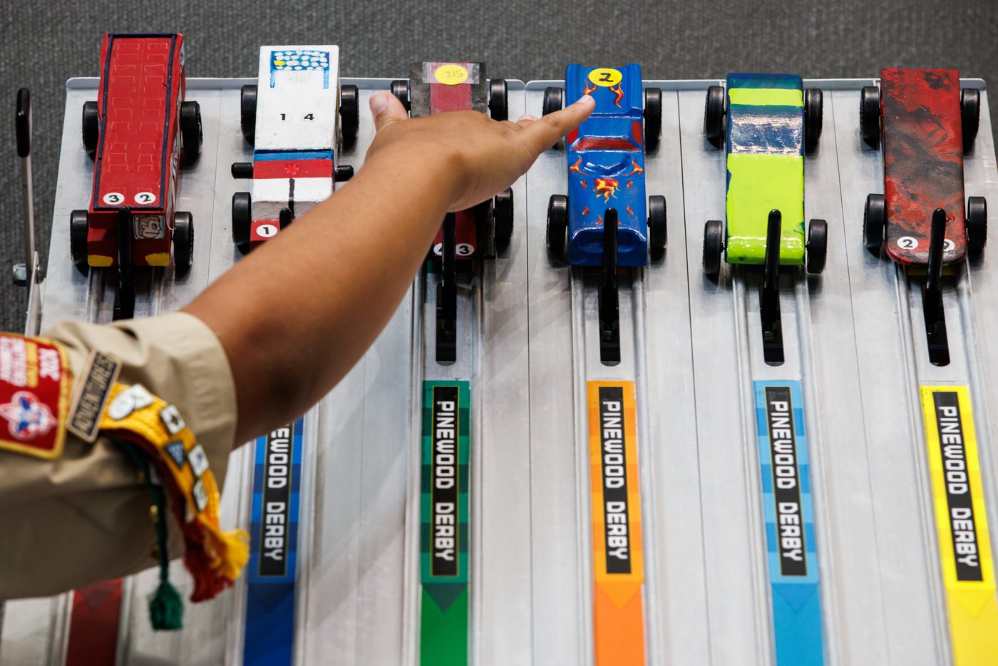 Hand-painted Pinewood Derby cars lined up on the track before a race.